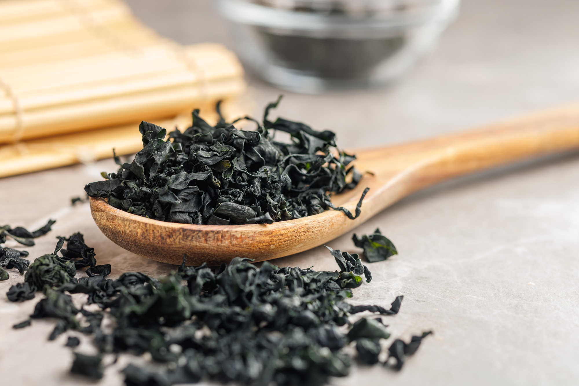 Dried wakame seaweed in spoon on kitchen table.